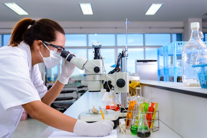 Profesional de la industria farmacéutica usando microscopio